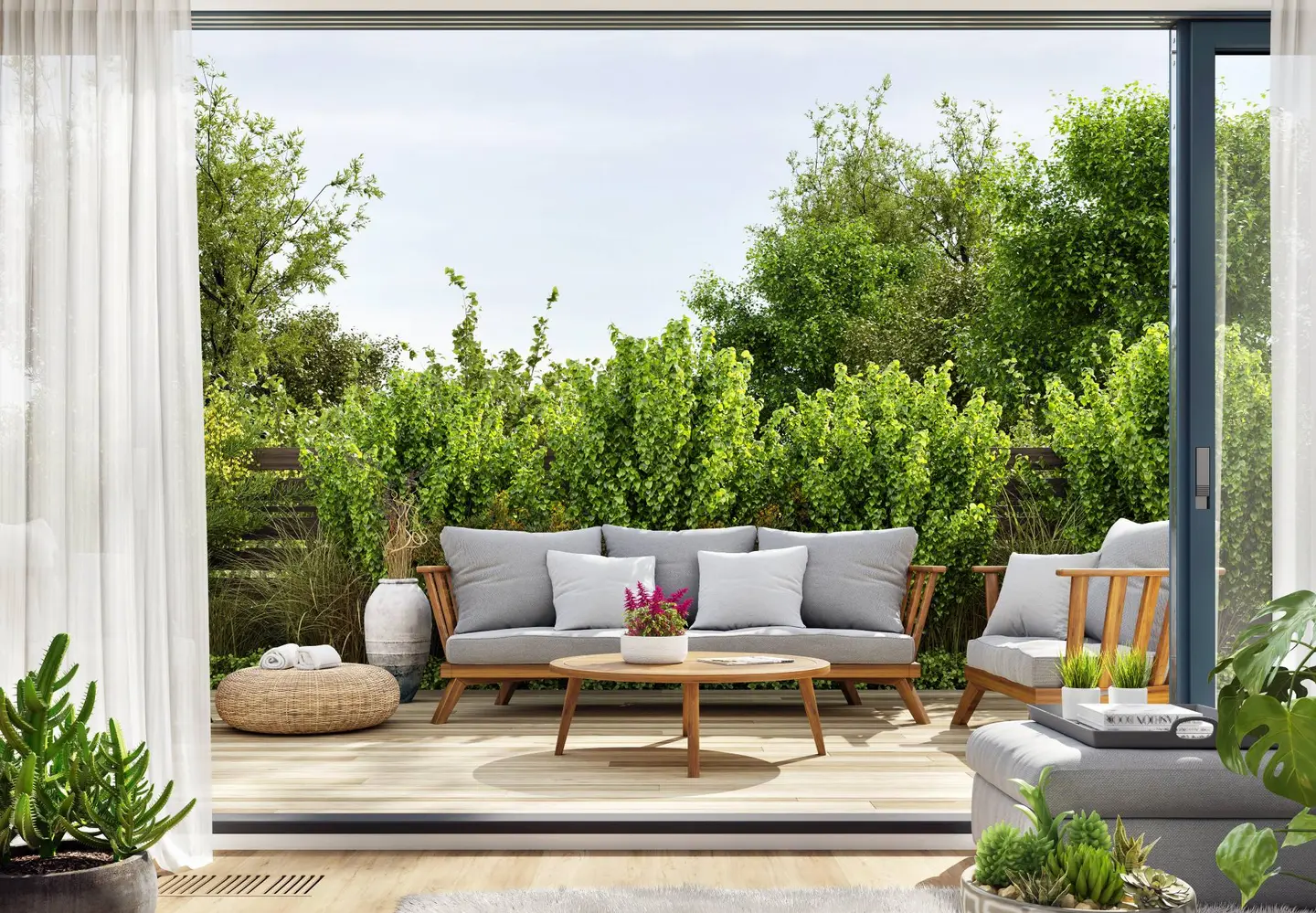 Eine Terrasse mit zwei stilvollen Sofas, buntem Blumenschmuck und Pflanzen im Vordergrund.
