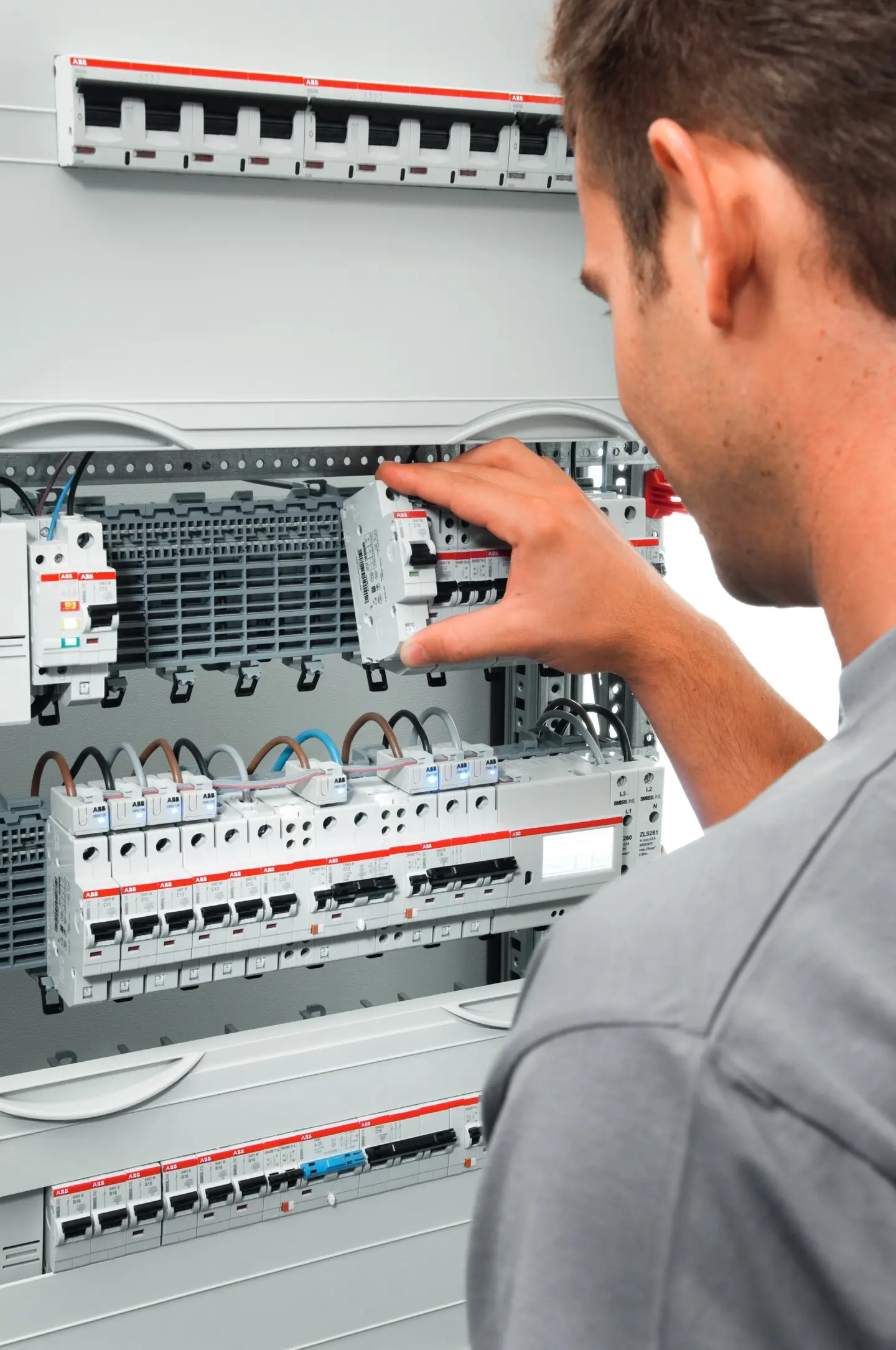 Ein Techniker überprüft einen elektrischen Schaltschrank mit mehreren Schaltern und Sicherungen.