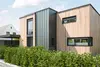 Modernes Haus mit Holz- und Metallelementen, großen Fenstern und begrünter Auffahrt.
