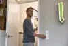 Mann öffnet eine Tür und erreicht einen Lichtschalter neben ihm.